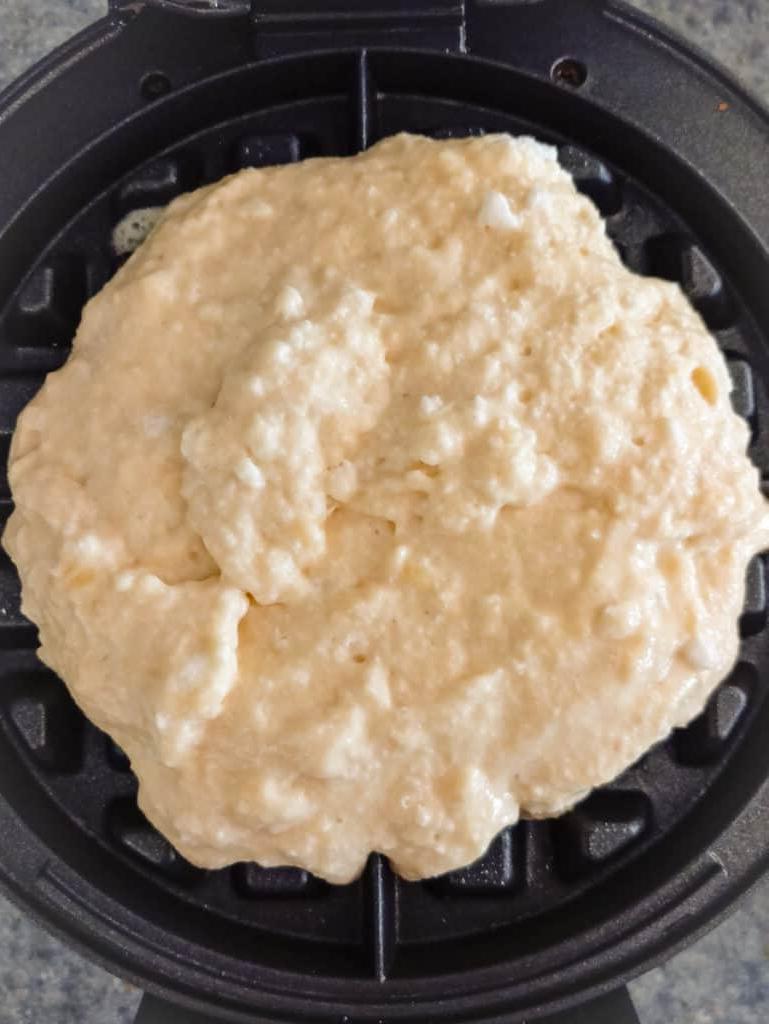 batter on a waffle iron ready to cook.
