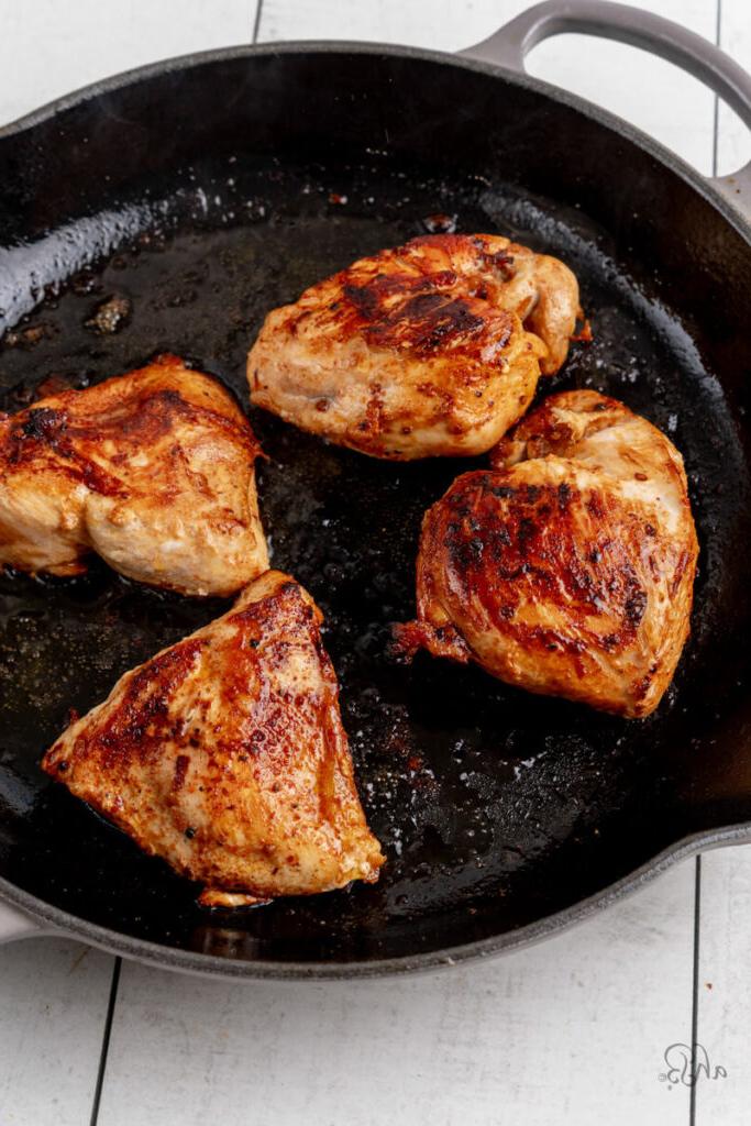 The cooked chicken is browned and cooked with oil in the skillet.