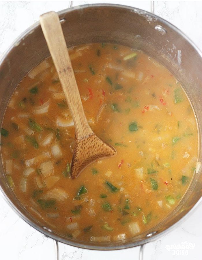 stirring crawfish filling in a stock pot with a wooden spoon