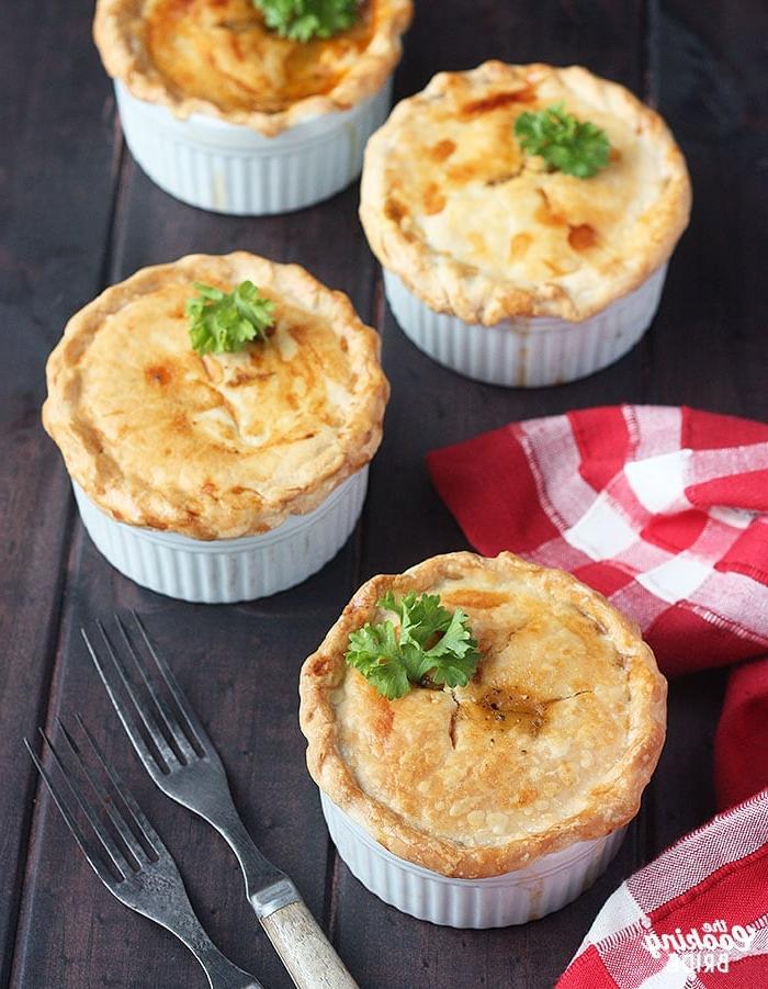 three baked crawfish pies on a wooden background with a red plaid napkin