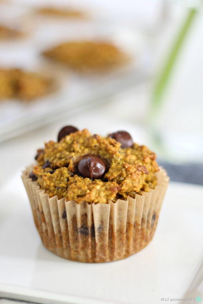 up close of a gluten free pumpkin muffin with chocolate chips with more muffins in a muffin tin behind it
