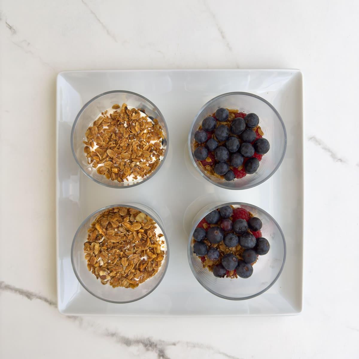 The next layer of ingredients in a yogurt parfait, berries and granola with yogurt.