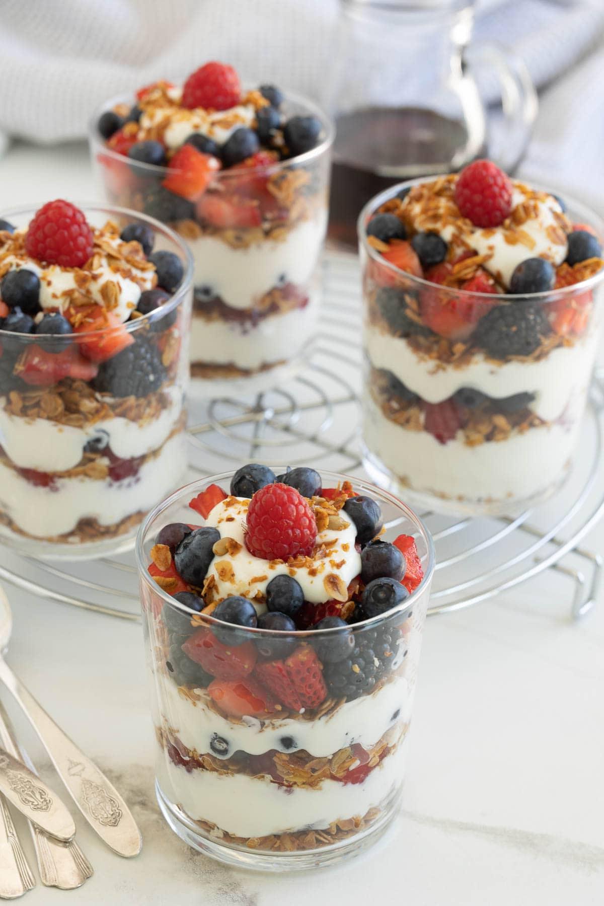 Colorful Greek yogurt parfaits in glasses with layers of granola, yogurt, and berries.
